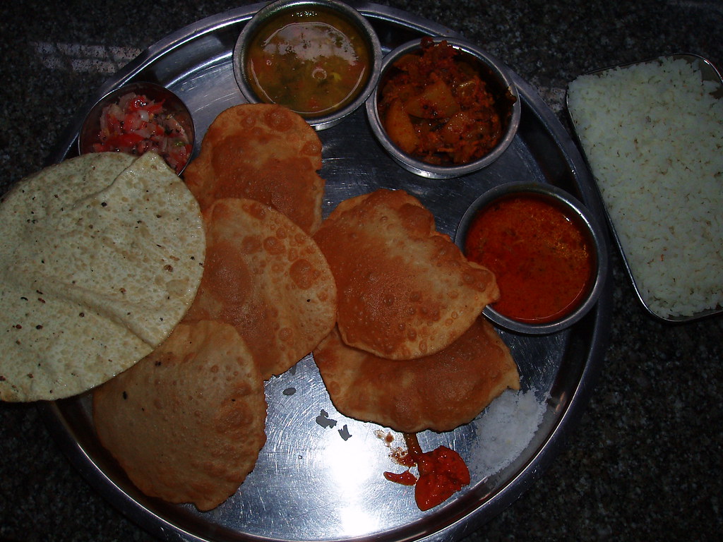 An Indian thali with many small bowls of curries, rice and bread